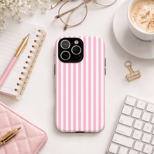 Tough phone case with pink and white stripes on a desk with a notebook, pen, glasses and coffee