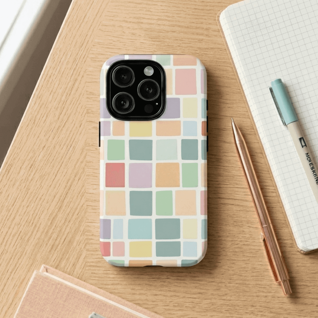 iPhone 16 Pro tough case with pastel checkered pattern on a wooden surface with a pen and notebook