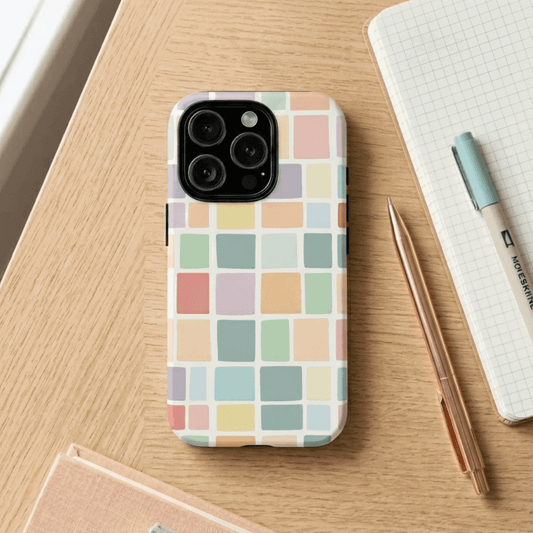 iPhone 16 Pro tough case with pastel checkered pattern on a wooden surface with a pen and notebook